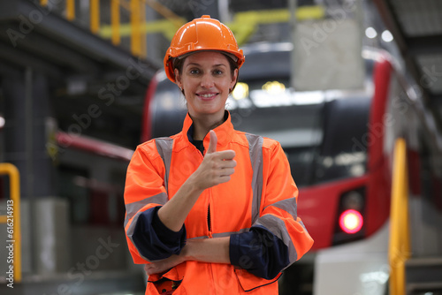 Woman Rail engineering on electric train station wearing orange helmet and jacket.    on-site, beautiful woman professional rail engineer close-up portrait in front of an electric train background. photo