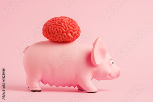 A model of a human brain on a pink toy pig on a pink background. Growing organs on animals concept.