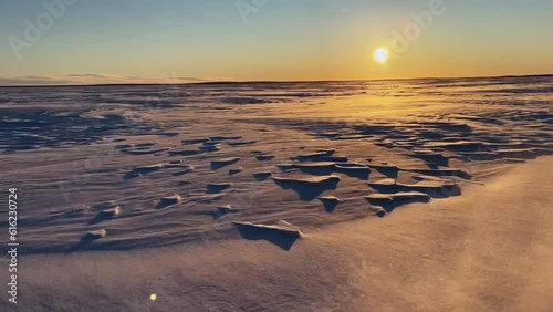 View from the snowmobile at speed. Large snowy field in winter. Evening sunset in Siberia. Red sun at sunset photo