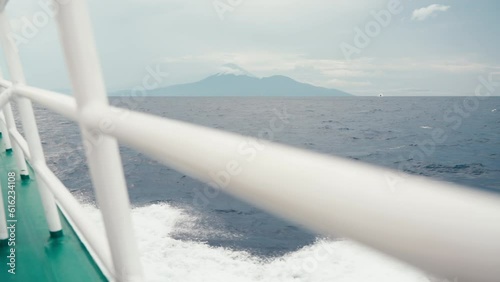 POV on board the ferry ship going to distant island with mountains. Fresh summer cruise. Voyage on stormy ocean on cloudy day. Transportation between island. White rail of vessel. Speedboat. Fast boat photo