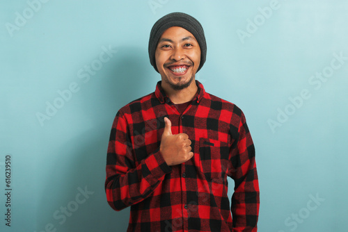 Fotografie Asian man with beanie hat and red plaid flannel shirt showing thumb up