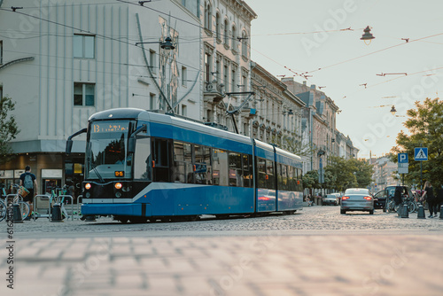 Blue public tram in the city of Krakow, Poland on early summer evening, riding through the streets of busy city. Modern tram in Polish city.