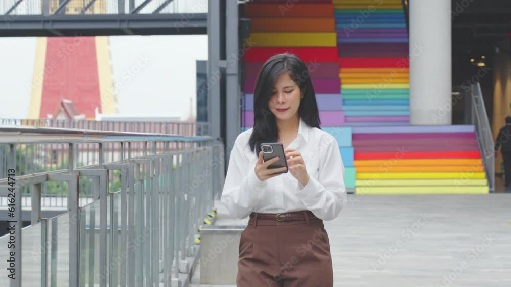 Beautiful business asian woman using smartphone to chatting with friend while walking in office building area. Beautiful business asian woman using smartphone to chatting with friend while walking in office building area.