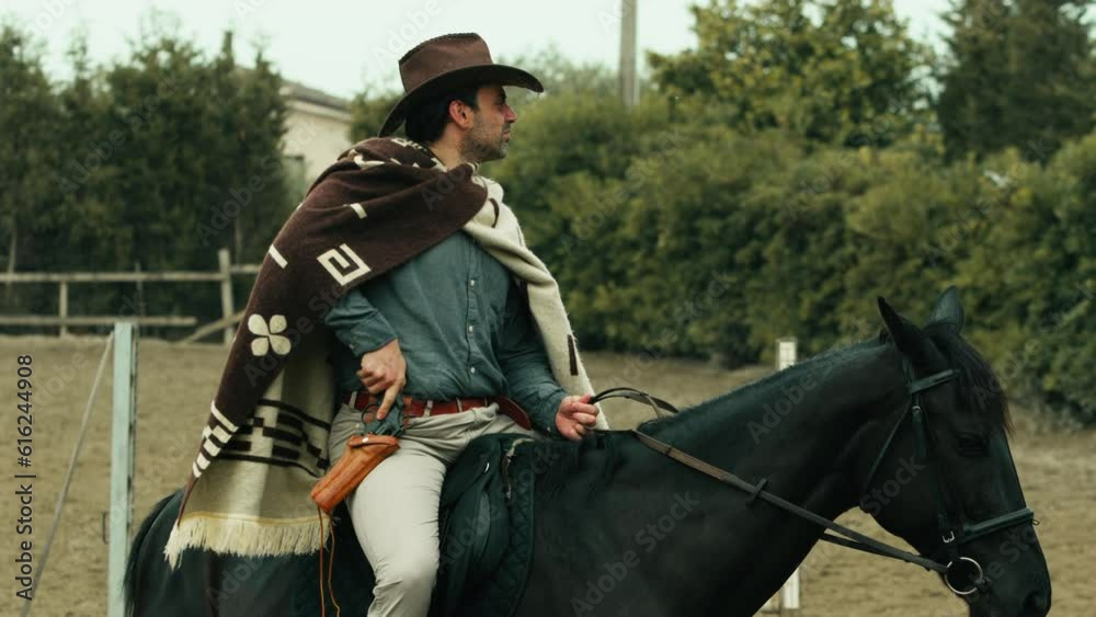 Cowboy holding the revolver gun on his black horse