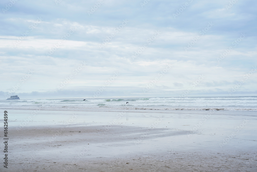 Beach along the Oregon Coast. Large boulder in ocean to the left of the image. Beach along the Oregon Coast. Large boulder in ocean to the left of the image.