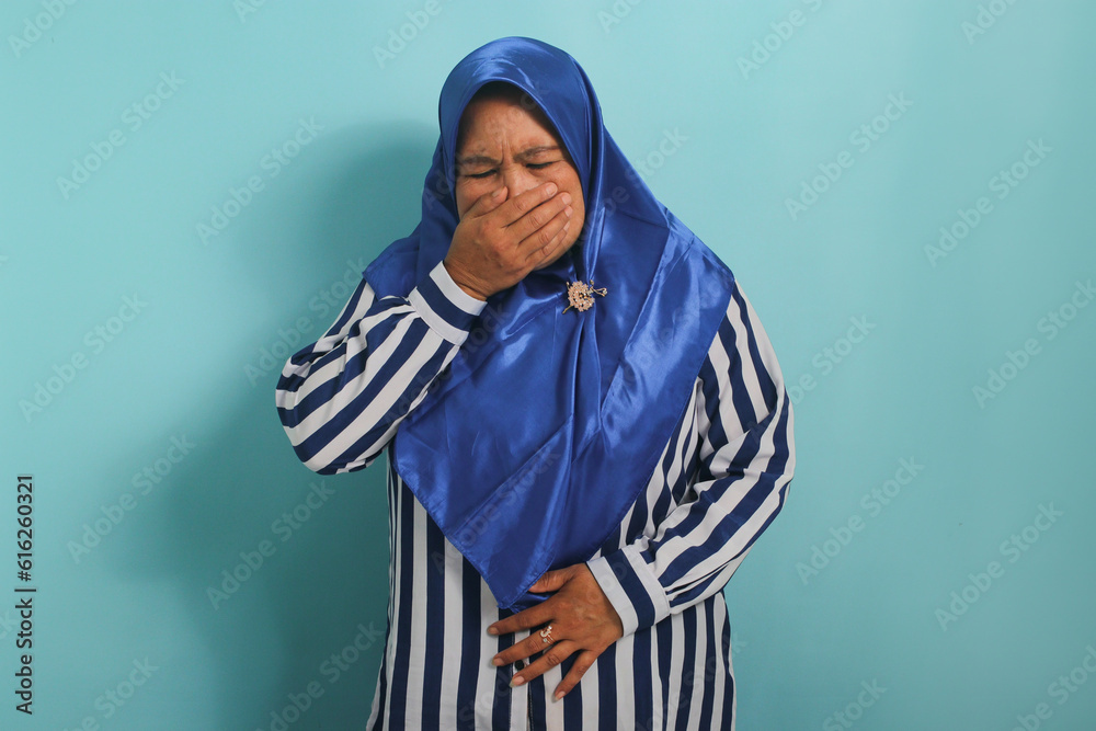 Portrait of a middleaged Asian woman in a hijab shows her clutching