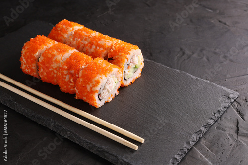 Sushi and rolls set on a black plate and black background