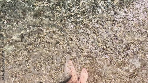 Slow motion as a man walks on the beach and the waves wash his feet, vacation on the Adriatic sea.