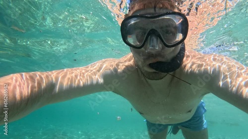 A guy with a mask and a snorkel dives in the Adriatic Sea on a sunny day.