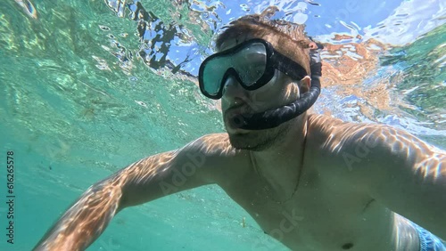 A guy with a mask and a snorkel dives in the Adriatic Sea on a sunny day.