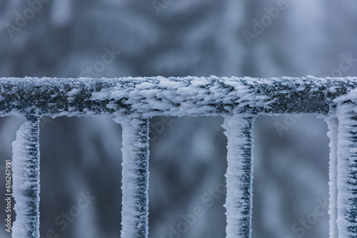 Metal railings of viewing tower covered with a lot of snow and ice faced to one side by strong wind