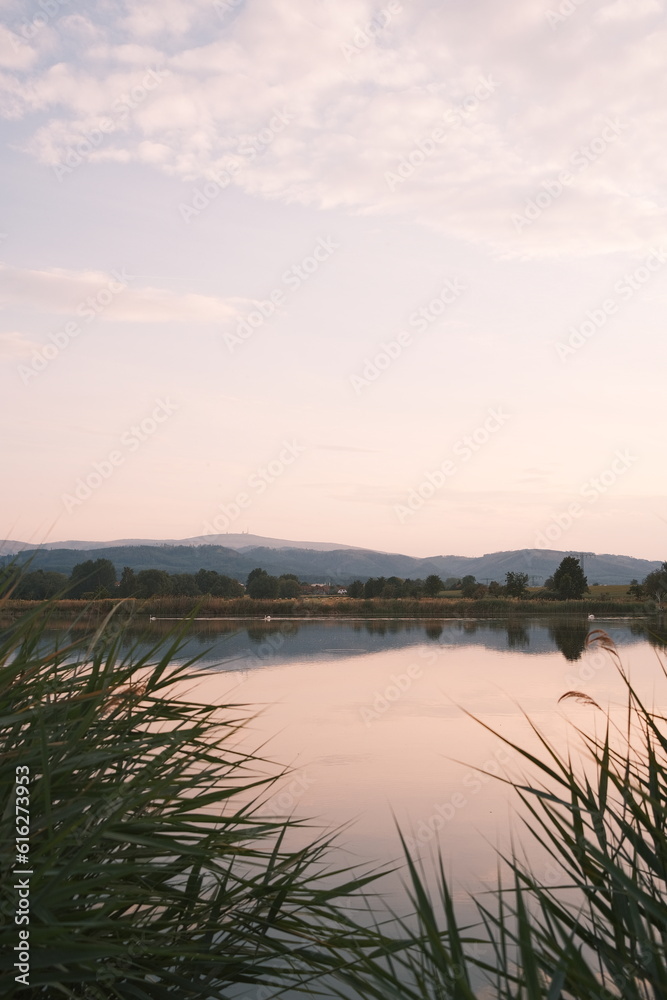Fototapeta premium Brockenblick an einem See bei Sonnenuntergang. Hochformat