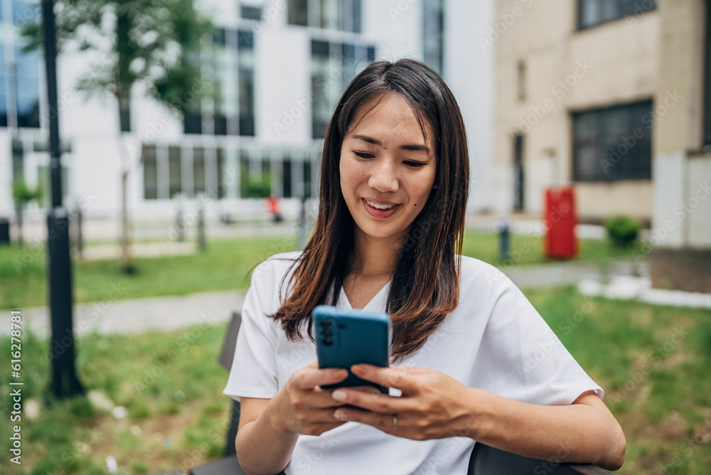 Young Japanese woman reading a message on the mobile phone in the city