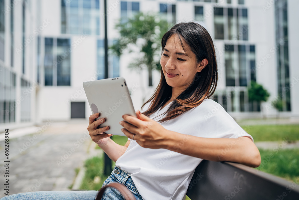 Young Japanese Business woman sitting in the street using a tablet and reading something
Young Japanese Business woman sitting in the street using a tablet and reading something
