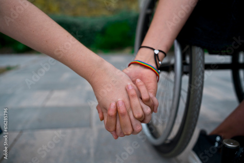 Crop woman holding hands with girlfriend using wheelchair