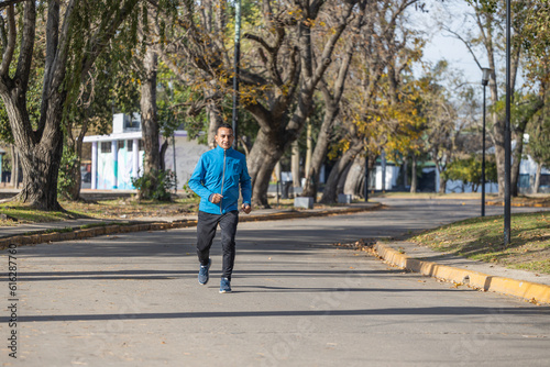 Latino man runs by a public park.