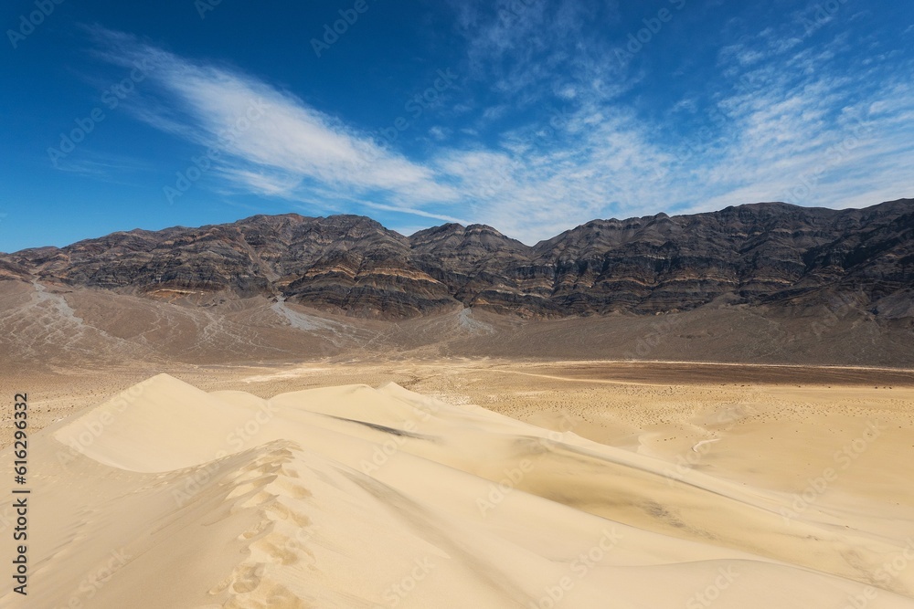 sand dunes in the desert, layered rock mountains and clouds