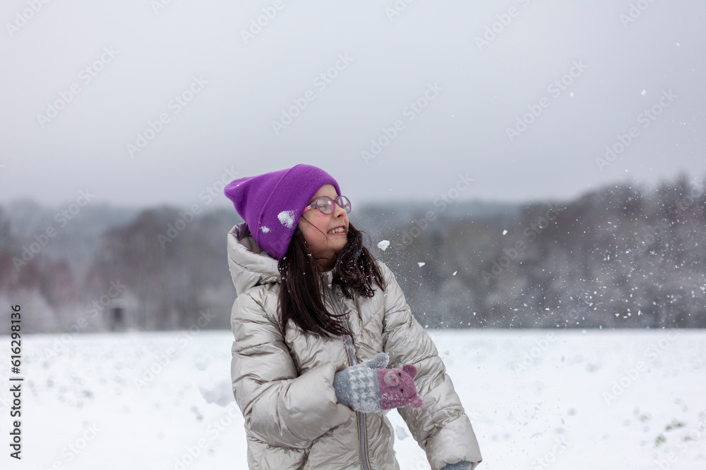 Portrait of a beautiful young girl in a winter park playing with snow Portrait of a beautiful young girl in a winter park playing with snow
