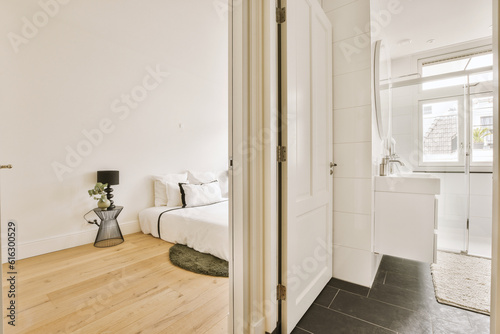 a bedroom with white walls and wood flooring in the room, as seen from the doorway to the bed