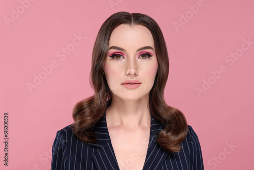 Portrait of beautiful young woman with makeup and gorgeous hair styling on pink background