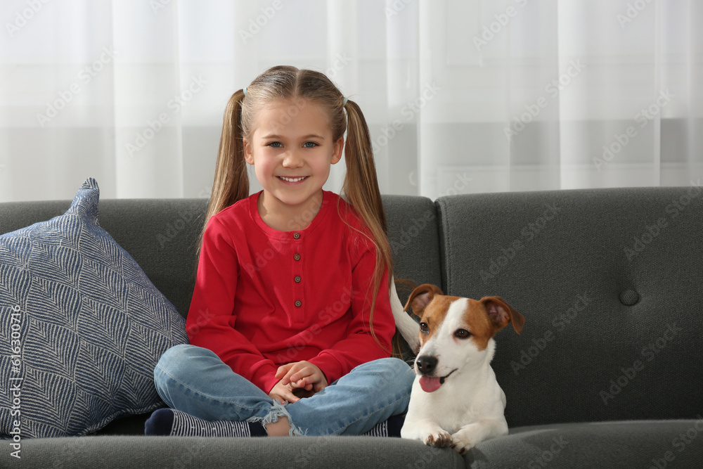 Cute girl with her dog on sofa at home. Adorable pet Cute girl with her dog on sofa at home. Adorable pet