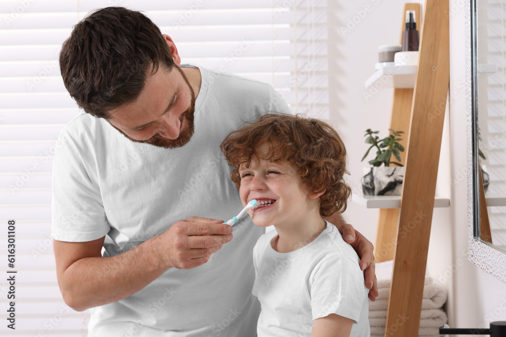 Fototapeta premium Father helping his son to brush teeth in bathroom