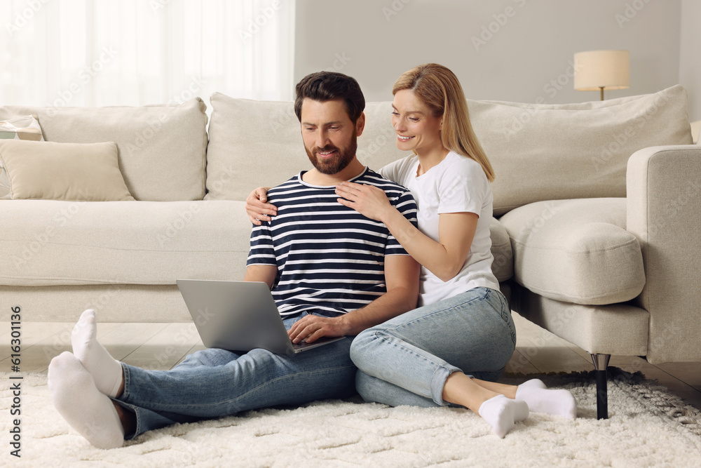 Happy couple with laptop on floor at home