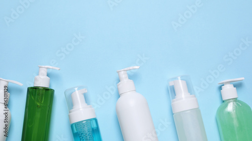 Different cleansers on light blue background, flat lay. Cosmetic product