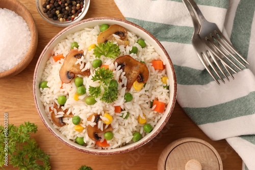 Foto Bowl of delicious rice with vegetables on wooden table, flat lay