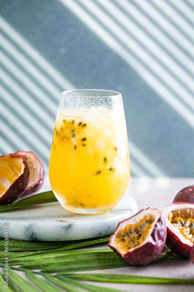 Glass of Iced passion fruit soda with lemon and passion fruit half slice on a light background, refreshing drink or beverage with ice Glass of Iced passion fruit soda with lemon and passion fruit half slice on a light background, refreshing drink or beverage with ice