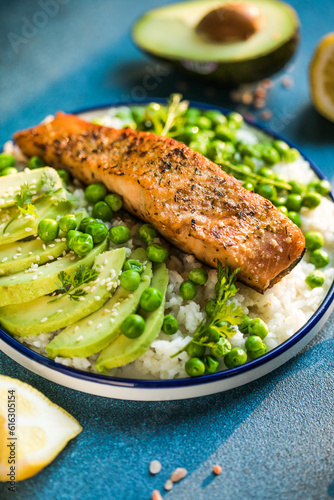 Poke bowl with rice, salmon,avocado and peas, sesame seeds on blue background
