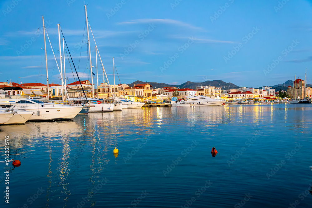 Evening view of the boats in the harbor port and the illuminated seaside village shops and cafes on the Saronic island of Aegina, Greece.	
