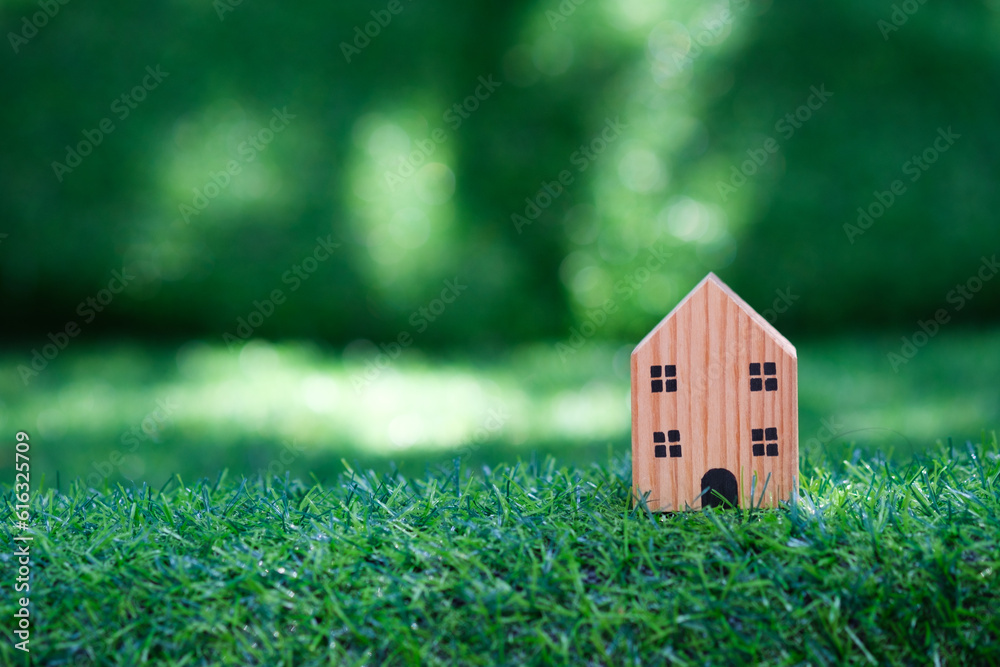 Eco friendly house concept with model home outdoors in a garden with copy space green bokeh background. Eco or ecology life  concept.