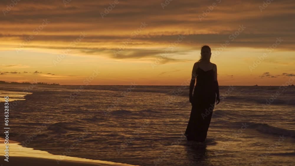 Young happy romantic girl is walking at sunset beach. Full length. Back view. Young happy romantic girl is walking at sunset beach. Full length. Back view.