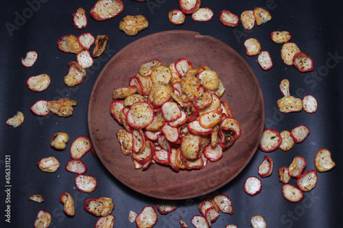 pile of fried spicy onion chips snacks on a brown wooden plate