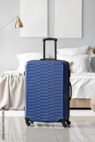 Blue suitcase in light bedroom