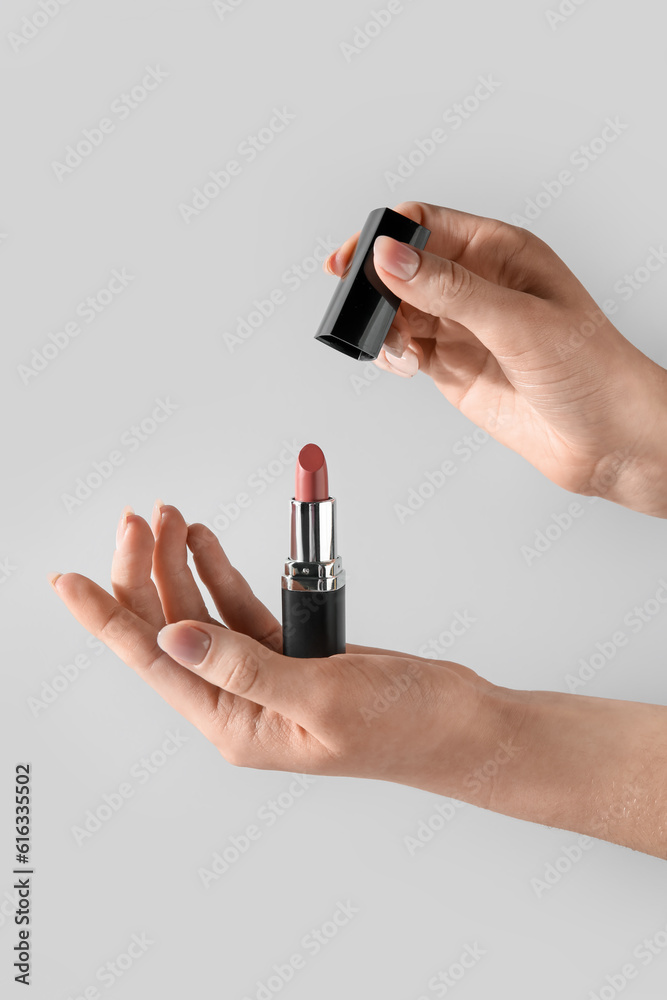 Female hand holding lipstick on white background Female hand holding lipstick on white background