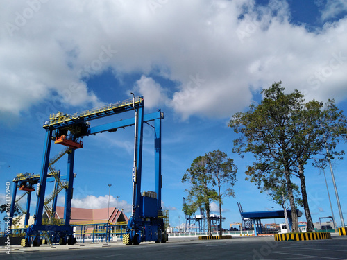 A blue rubber-wheeled crane used to lift containers.