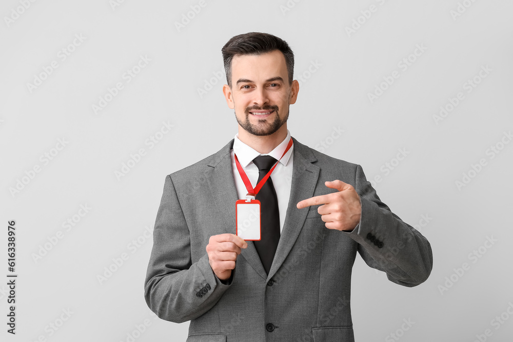 Young businessman pointing at blank badge on light background Young businessman pointing at blank badge on light background