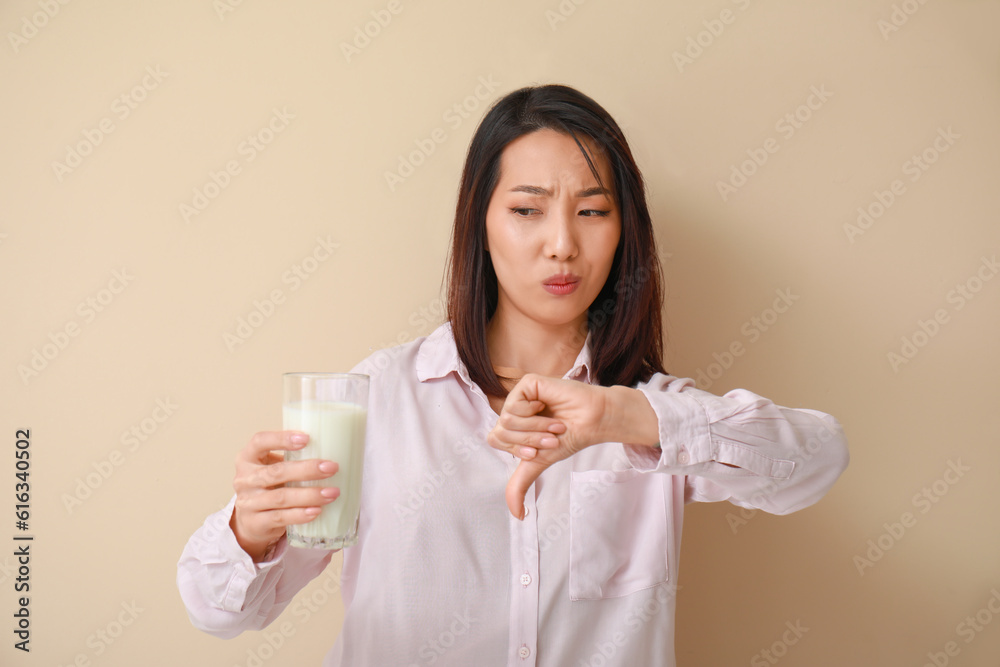 Young Asian woman with lactose intolerance on beige background Young Asian woman with lactose intolerance on beige background