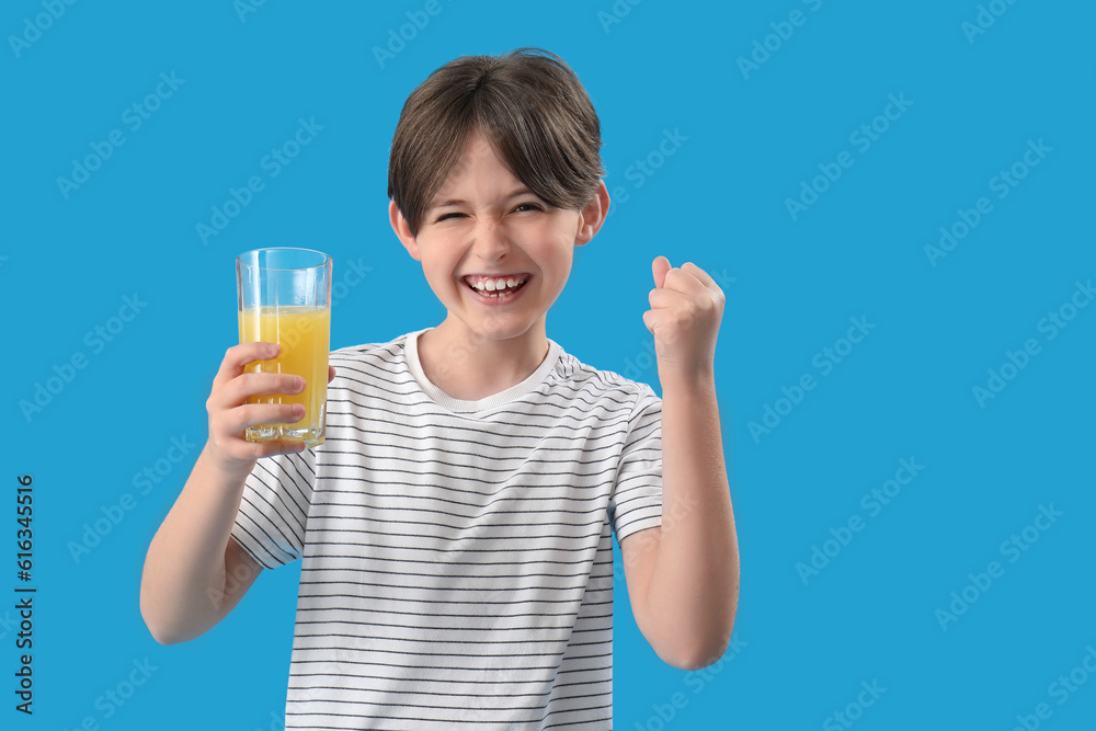Happy little boy with glass of orange juice on blue background Happy little boy with glass of orange juice on blue background