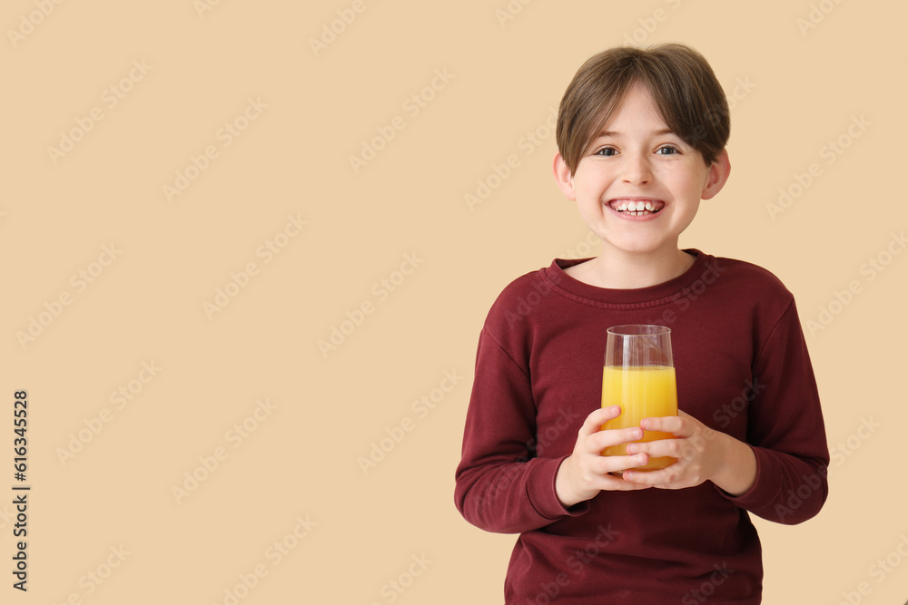 Little boy with glass of orange juice on beige background Little boy with glass of orange juice on beige background