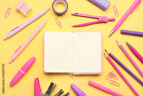 Notebook with different school stationery on yellow background