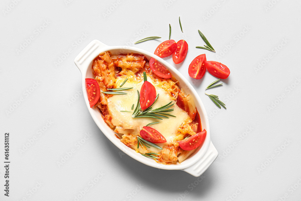 Baking dish of pasta with tomato sauce and cheese on white background