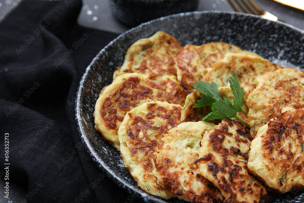Bowl with tasty zucchini fritters on table Bowl with tasty zucchini fritters on table