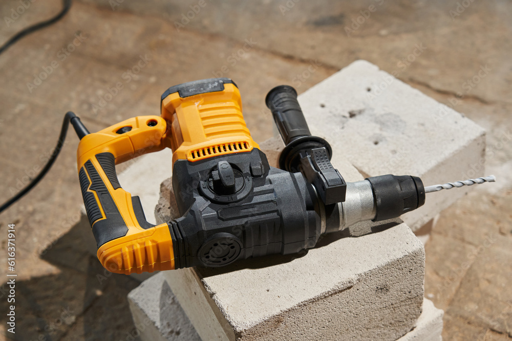 a powerful drill puncher with a drill lies on concrete blocks