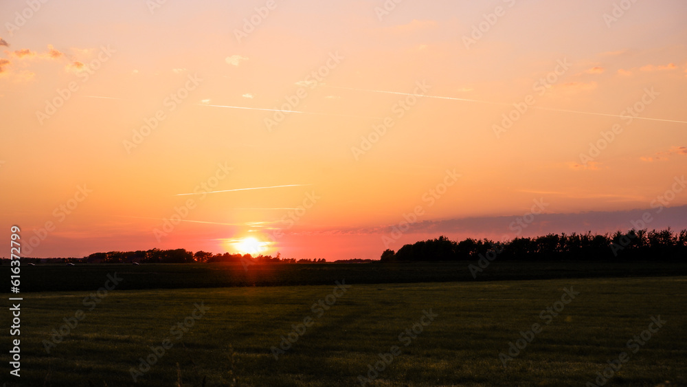 Landscape, sunny dawn in a field. Hay in the field, evening sunset and clear sky in summer