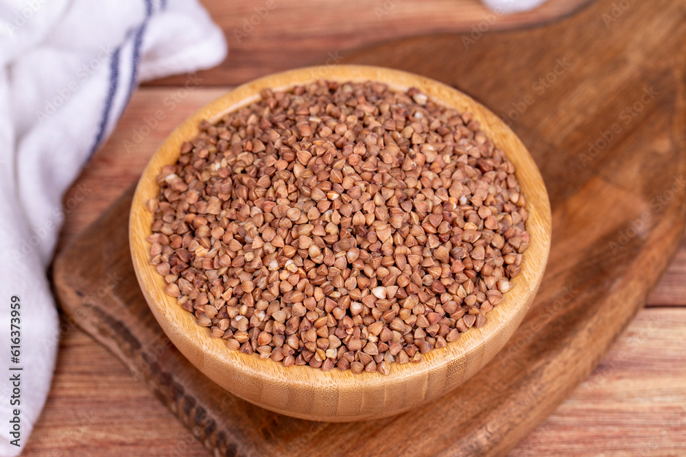 Buckwheat on wood background. Buckwheat grains in wooden bowl