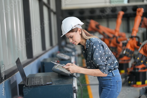 Portrait of Female Automotive Industry 4.0 Engineer in Safety Uniform Using Laptop at Car Factory Facility. Assembly Plant. engineer working at automated AI robotic production factory..