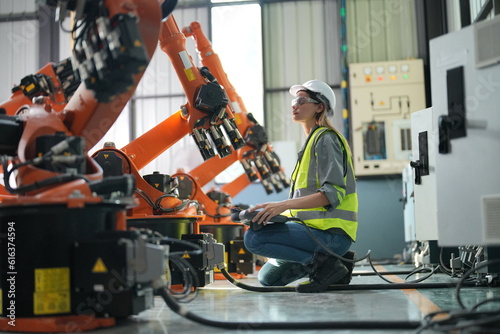 Portrait of Female Automotive Industry 4.0 Engineer in Safety Uniform Using Laptop at Car Factory Facility. Assembly Plant. engineer working at automated AI robotic production factory..